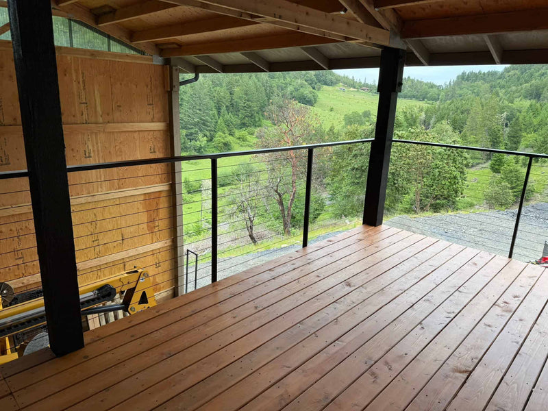 Custom black steel and wire hand rails on customers deck overlooking beautiful outdoor scene.