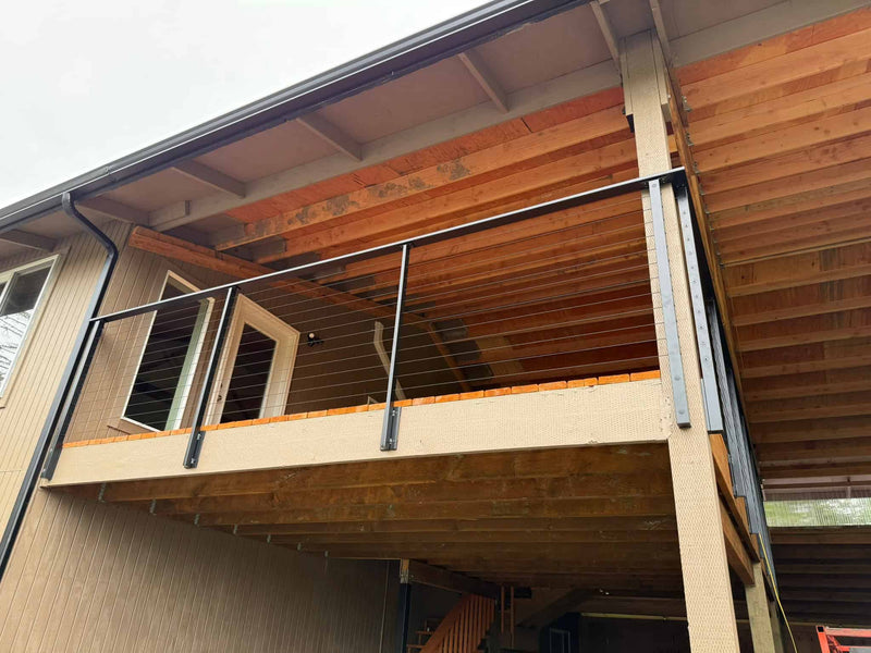 Custom black metal and wire railing on wood deck.