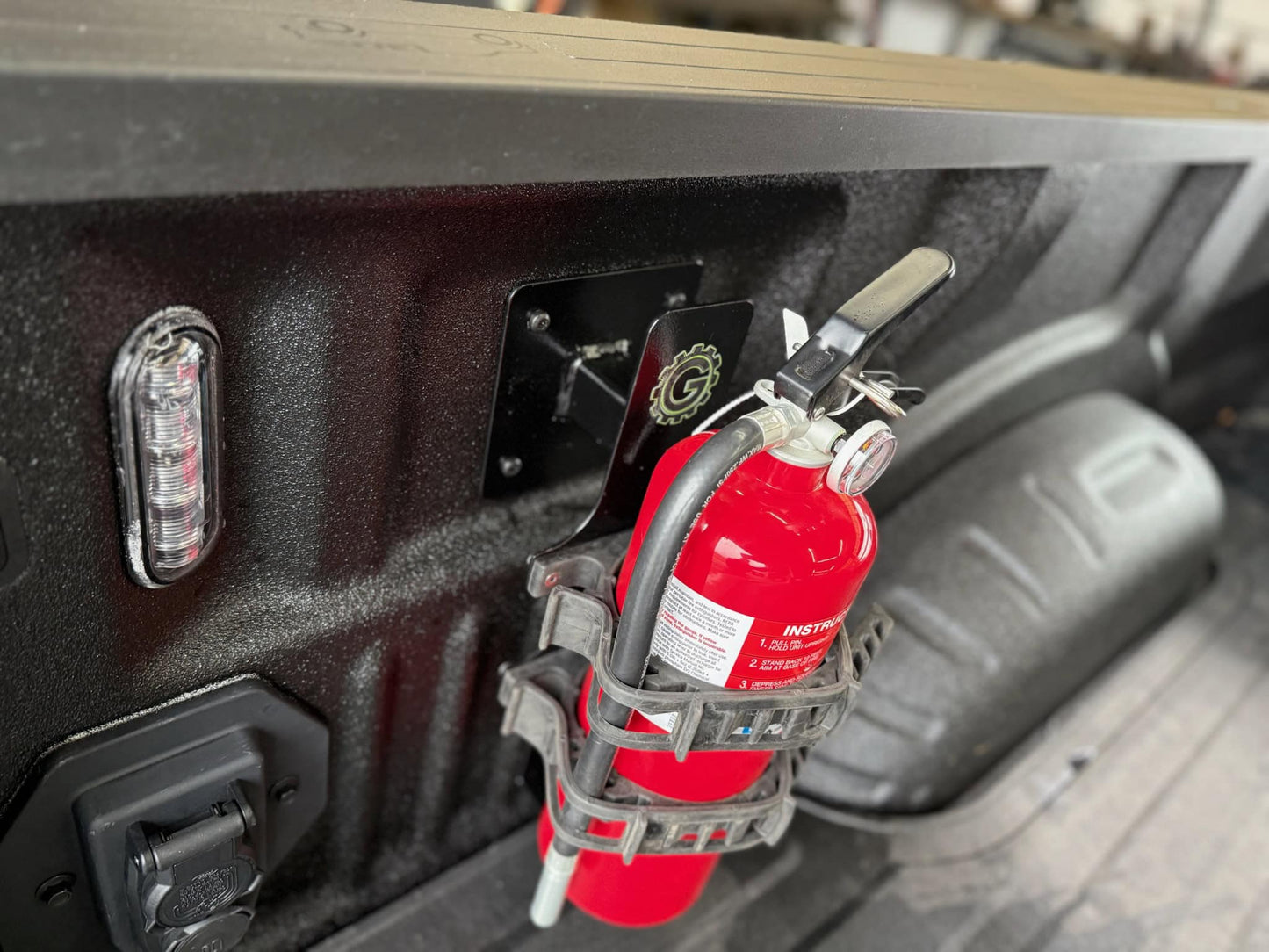 Fire extinguisher mounted on a vehicle's bed with a visible Gheer brand logo.