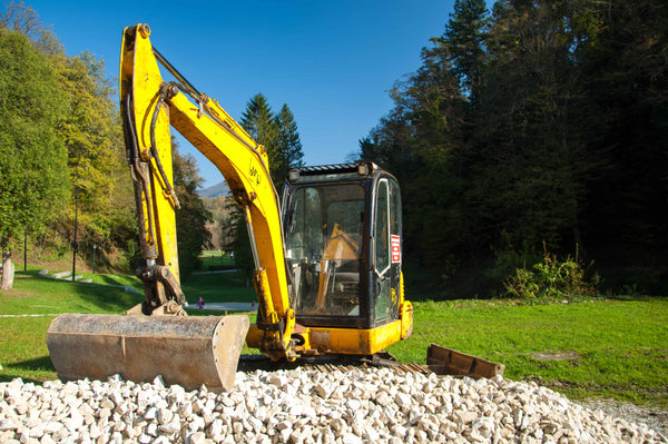 Excavator clearing the ground to prep site for installation of custom fence