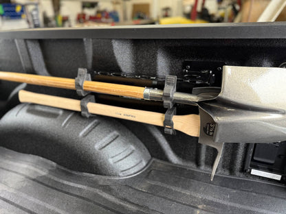 Shovels and Fire Polaski held in place by a tool holder in a truck bed.