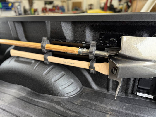Shovels and Fire Polaski held in place by a tool holder in a truck bed.