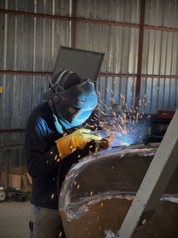 Person welding custom repair job in metal fabrication shop. Roseburg Oregon Gheer Built